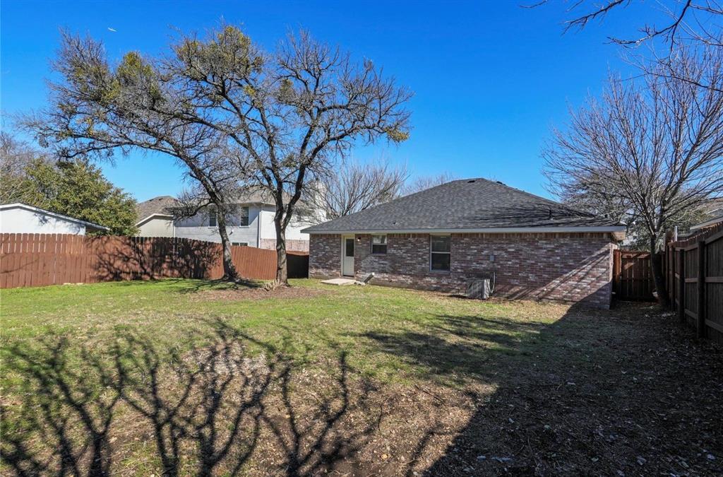 5169 East Rim Road Dallas, TX 75211 - Photo 18 of 19 Expansive backyard featuring a manicured lawn, established trees, and perimeter fencing