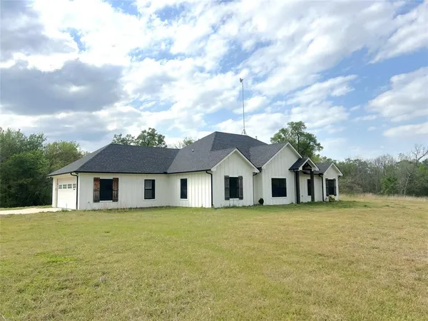 a white house with a big yard and large trees