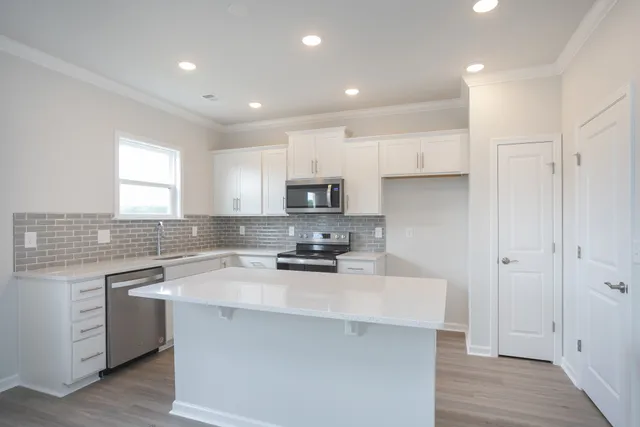 a kitchen with a sink a stove a refrigerator and white cabinets