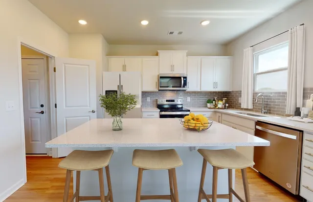 a kitchen with stainless steel appliances granite countertop a table and chairs in it