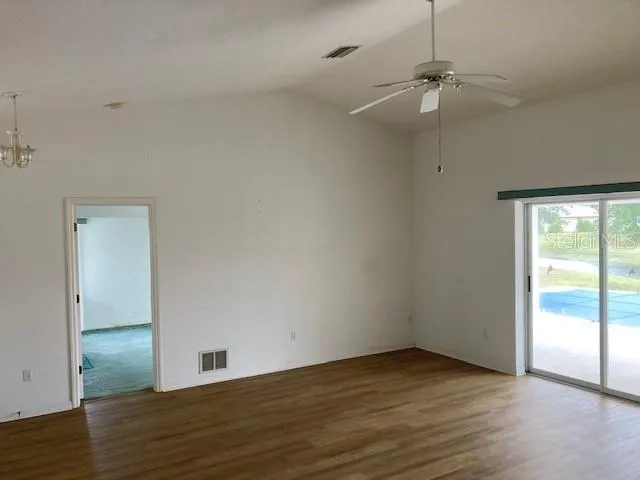 an empty room with wooden floor fan and windows