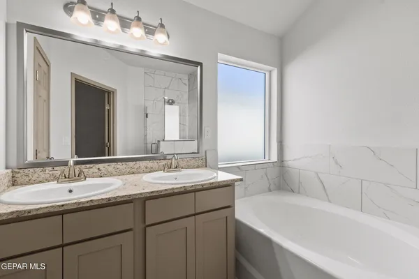 a bathroom with a sink double vanity granite tub and a mirror