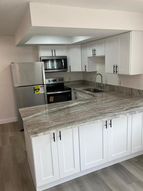 6125 Chesham Drive, Unit 1 New Port Richey, FL 34653 - Photo 14 of 39 a kitchen with stainless steel appliances granite countertop a sink a microwave a refrigerator and white cabinets