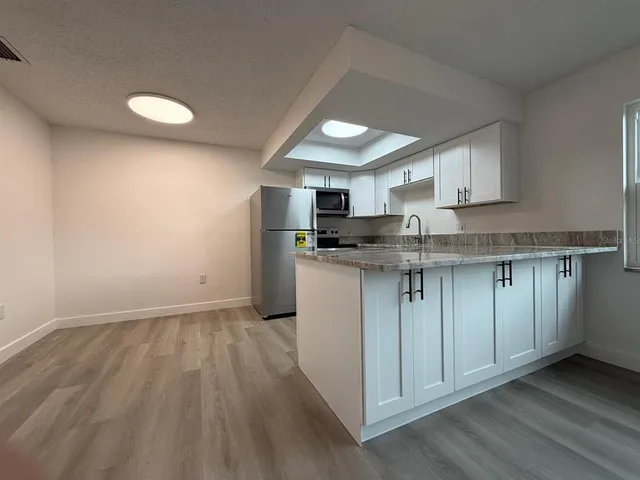 a view of a hallway with wooden floor and a kitchen