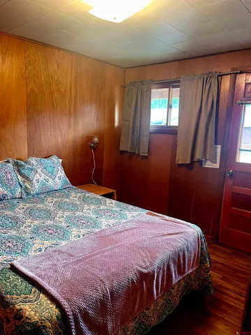 a bedroom with a bed lamps and wooden floor