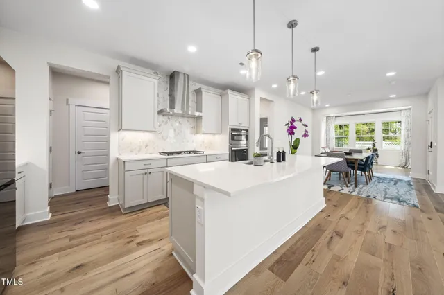 a kitchen with stainless steel appliances a stove top oven a refrigerator cabinets and wooden floor