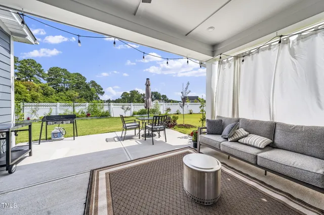 a view of a patio with couches table and chairs with wooden floor and fence