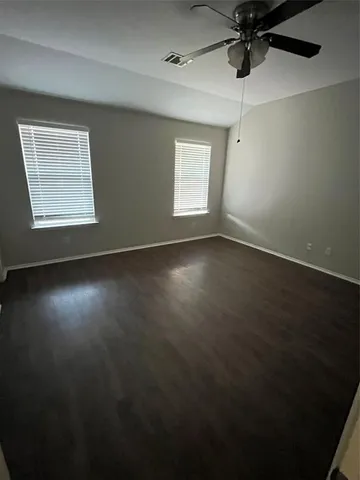 en empty room with windows and ceiling fan