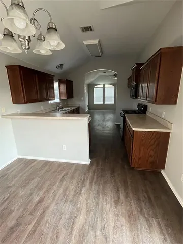 a living room with stainless steel appliances kitchen island granite countertop a sink dishwasher stove and microwave with wooden floor
