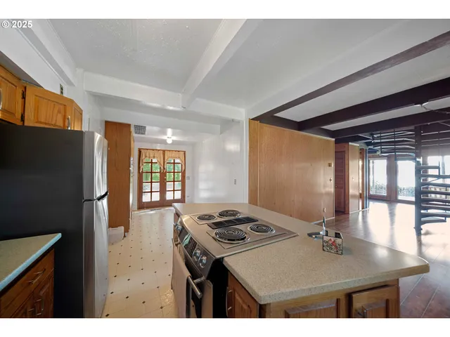 a kitchen with a refrigerator a stove a window and a dining table