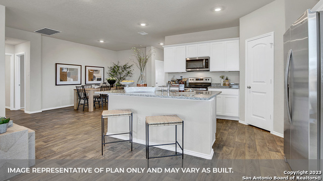 1008 Village Run Seguin, TX 78155 - Photo 14 of 39 a kitchen with stainless steel appliances granite countertop a stove top oven a sink a refrigerator and white cabinets with wooden floor
