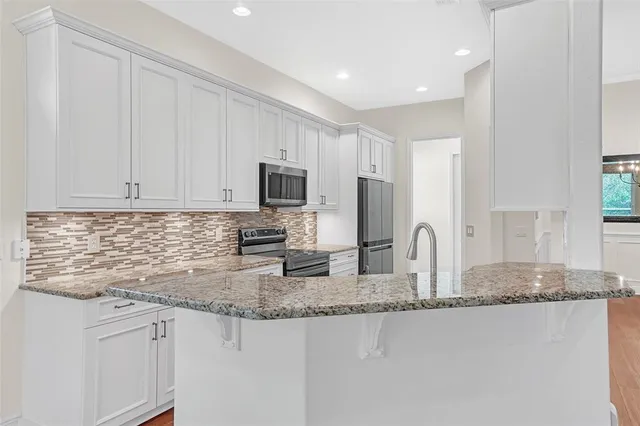 a kitchen with kitchen island granite countertop a sink cabinets and stainless steel appliances