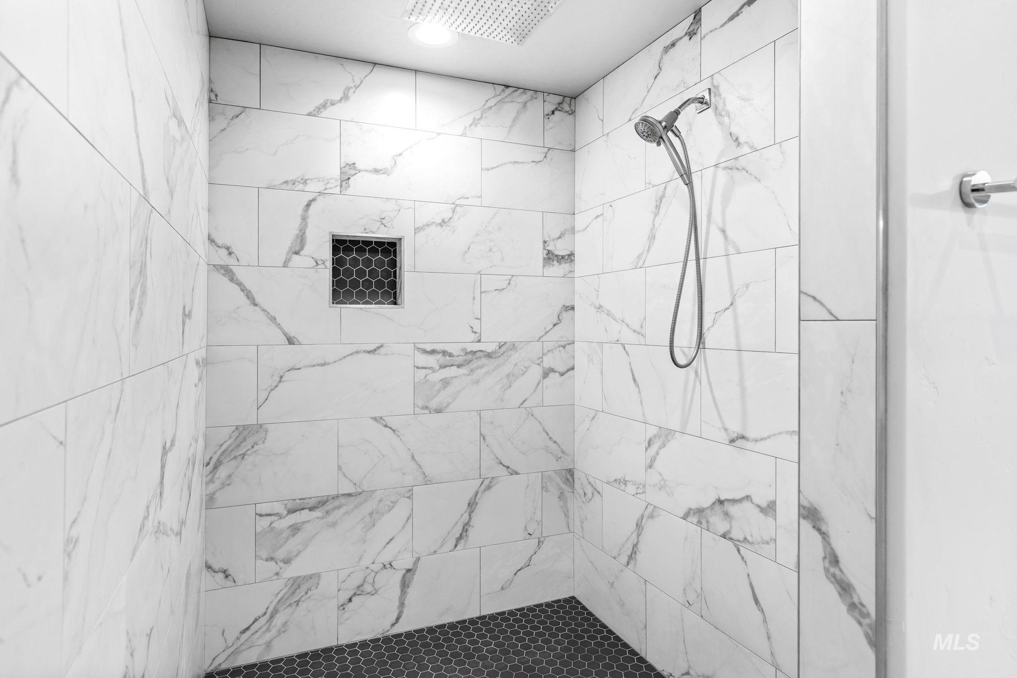 2934 East Murchison Street Meridian, ID 83642 - Photo 26 of 44 Shower enclosure featuring large format marble-look tile walls, a hexagonal tile floor, and a recessed niche with coordinating hexagonal tile