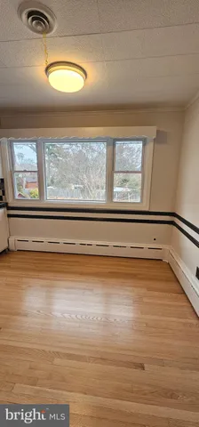 a view of empty room with window and wooden floor