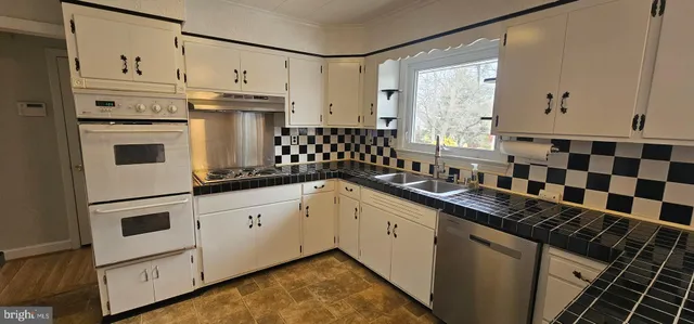 a kitchen with granite countertop white cabinets and white appliances