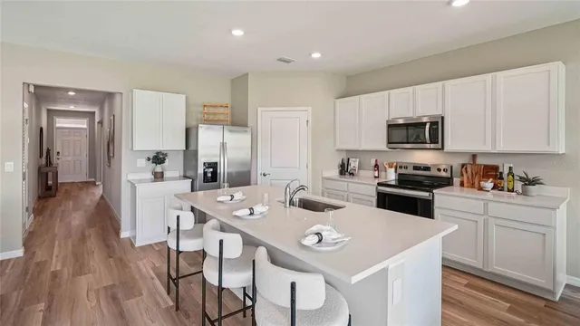a kitchen with a sink a stove a refrigerator and white cabinets with wooden floor