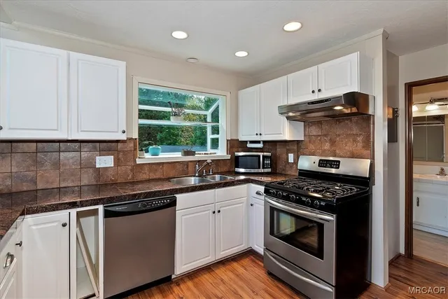 a kitchen with stainless steel appliances granite countertop a stove a sink and a microwave