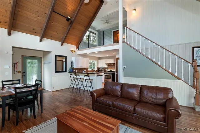 a living room with furniture and a dining table with wooden floor