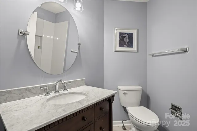a bathroom with a granite countertop toilet a sink and mirror