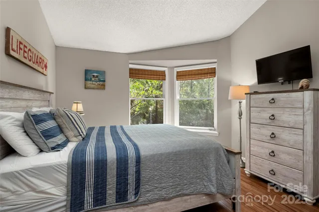 a bedroom with a bed and a flat tv screen on dresser