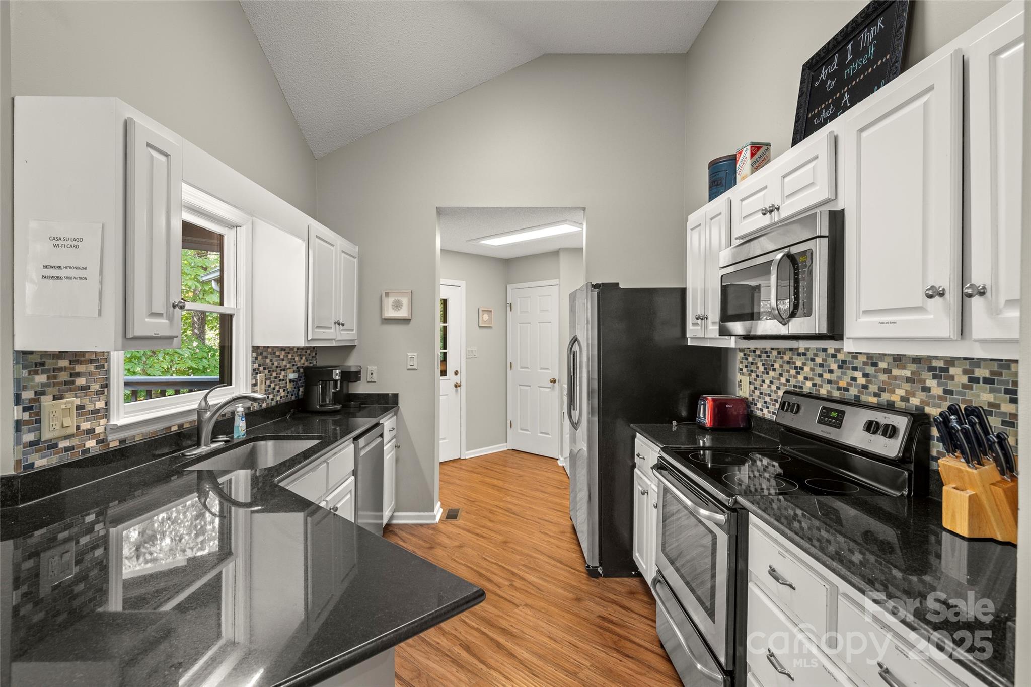 212 Ridgeway Road Lake Lure, NC 28746 - Photo 42 of 44 a kitchen with stainless steel appliances a stove a sink a refrigerator white cabinets and wooden floor