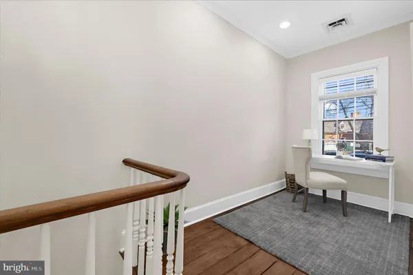 a view of a hallway with wooden floor and a bathroom