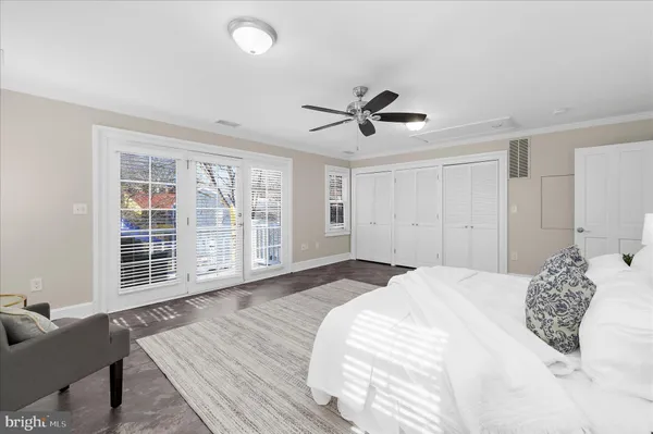 an empty room with wooden floor chandelier fan and windows