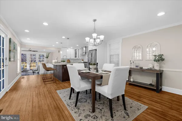 a kitchen with stainless steel appliances kitchen island granite countertop a refrigerator a stove a sink and a dining table with wooden floor