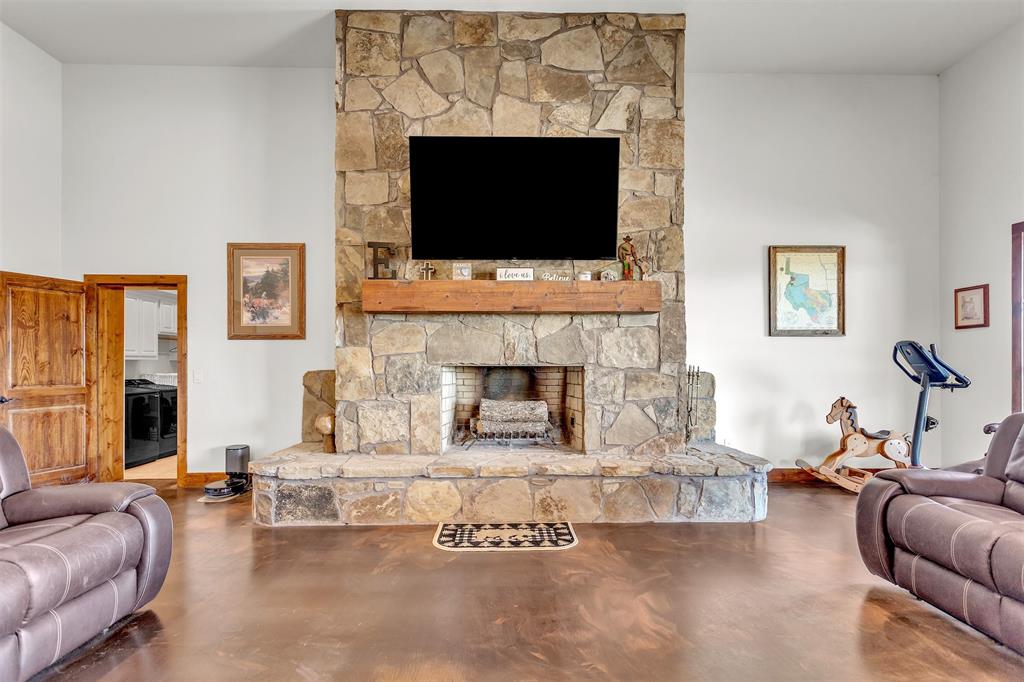13831 Friendship Road Pilot Point, TX 76258 - Photo 29 of 31 Living room with a floor to ceiling stone fireplace and concrete flooring, large ceiling fan in this open floor plan