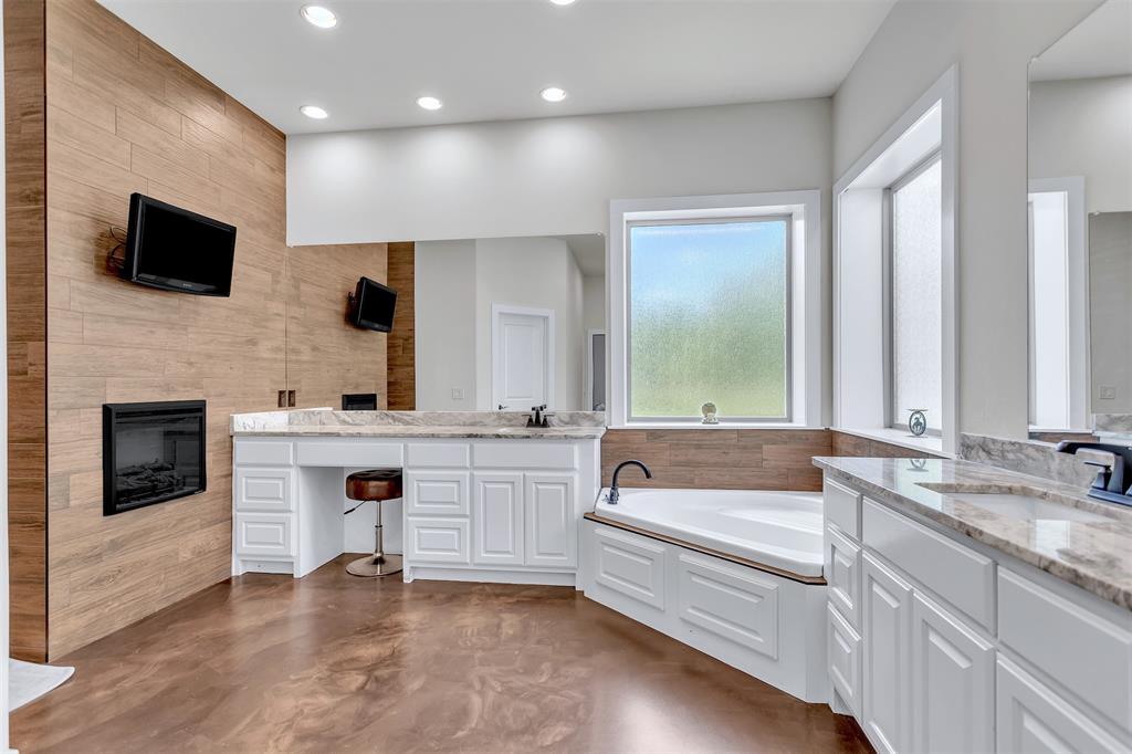 13831 Friendship Road Pilot Point, TX 76258 - Photo 12 of 31 Primary bath with a TV, fireplace, finished concrete floors, double vanities, a jetted bath, and recessed lighting