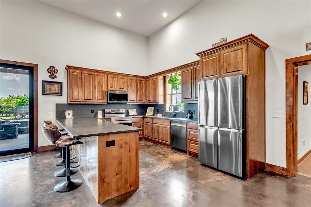 13831 Friendship Road Pilot Point, TX 76258 - Photo 2 of 31 a kitchen with stainless steel appliances granite countertop a refrigerator a sink dishwasher a stove a dining table and chairs with wooden floor