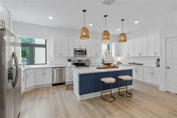 a open kitchen with white cabinets and stainless steel appliances