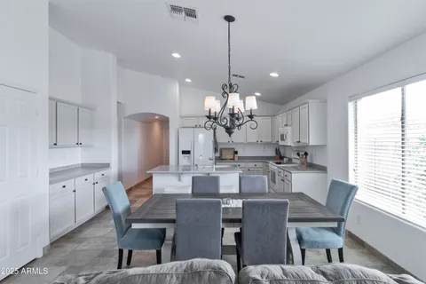 a view of a dining room and livingroom with furniture wooden floor a rug a fireplace and a chandelier