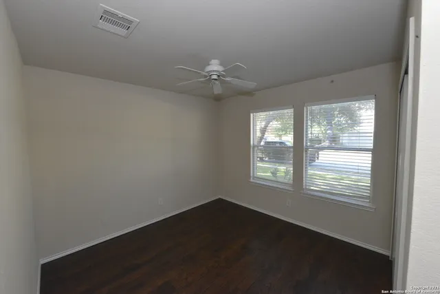 a view of an empty room with a window and a ceiling fan