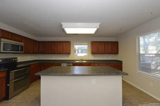 a kitchen with stainless steel appliances granite countertop a sink a stove a microwave a counter space and cabinets