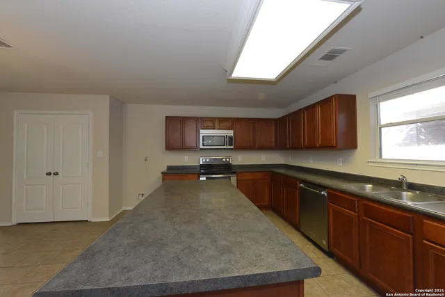a large kitchen with stainless steel appliances granite countertop a sink dishwasher stove and cabinets