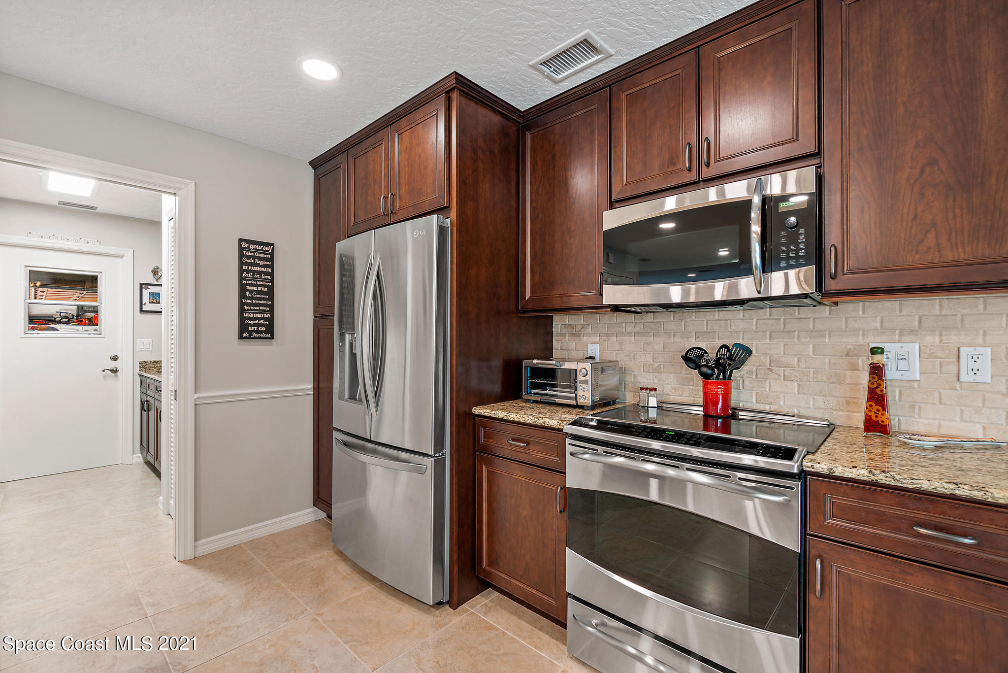 539 Lanternback Island Drive Satellite Beach, FL 32937 - Photo 13 of 54 a kitchen with granite countertop stainless steel appliances a stove microwave and refrigerator