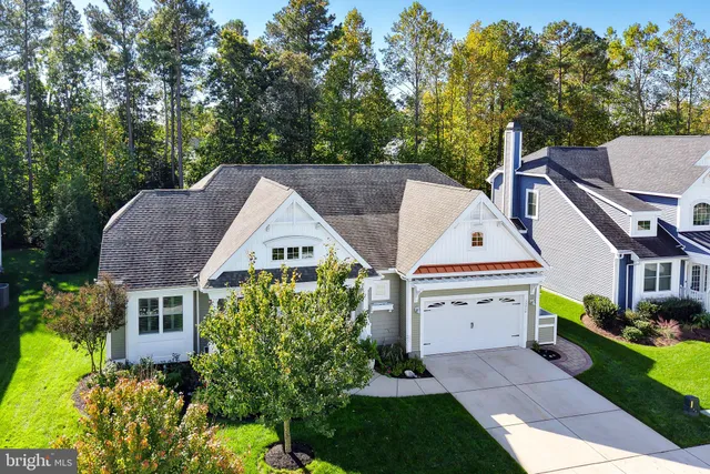 a view of a white house with a small yard plants and a large tree