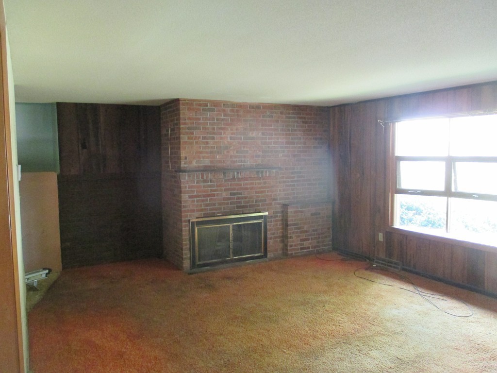 2 Barton Street Granby, MA 01033 - Photo 6 of 24 an empty room with a fireplace and windows