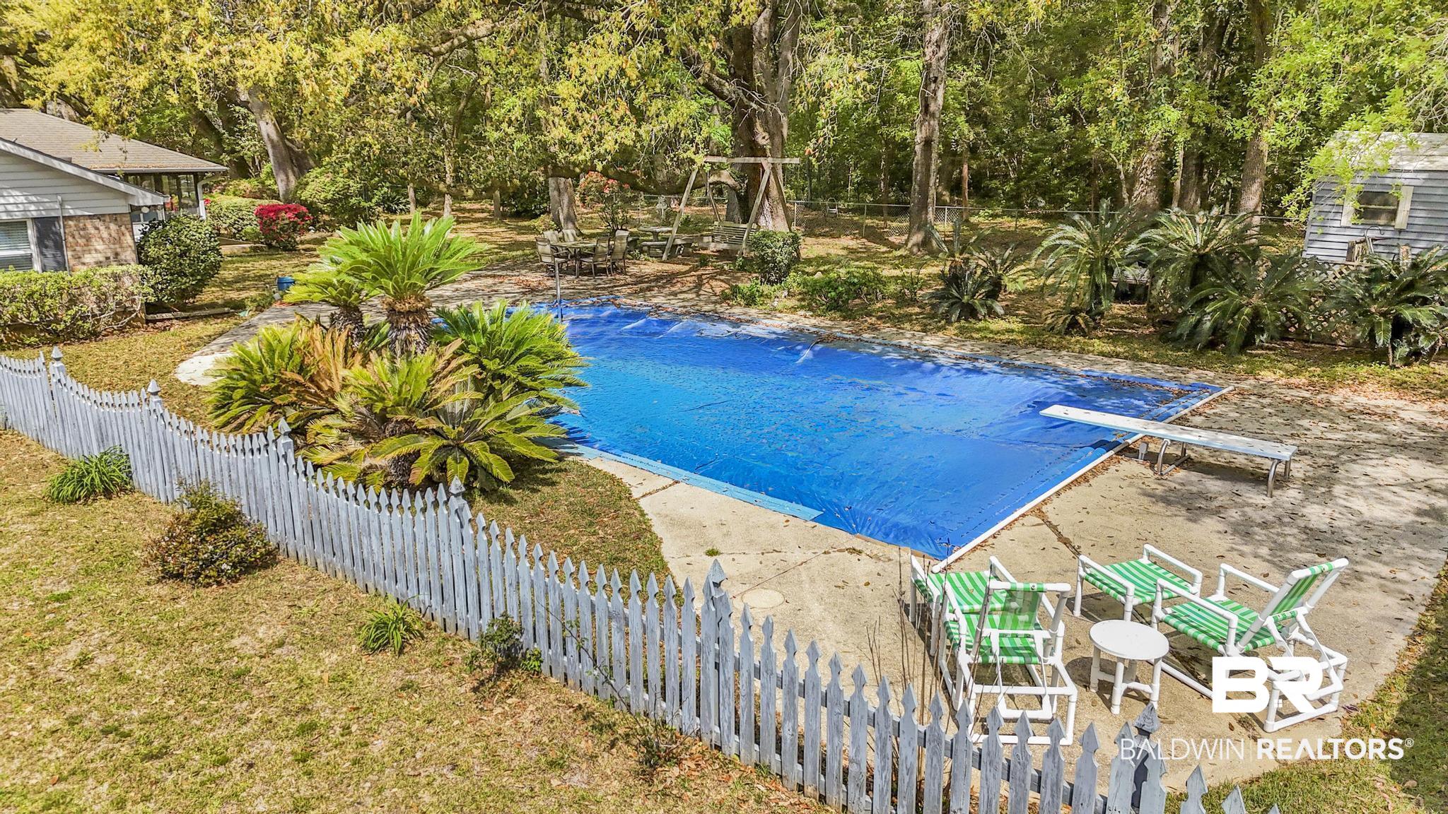 10207 Plantation Drive Daphne, AL 36526 - Photo 17 of 48 View of swimming pool featuring patio surround, a fenced backyard, a diving board, and view of wooded area