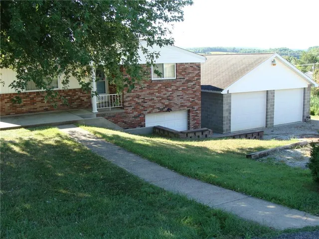 a view of a house with a yard and a large tree