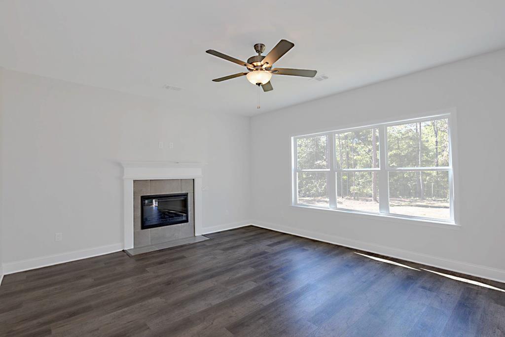 8705 McKee Road Upatoi, GA 31829 - Photo 5 of 42 an empty room with wooden floor a ceiling fan and windows