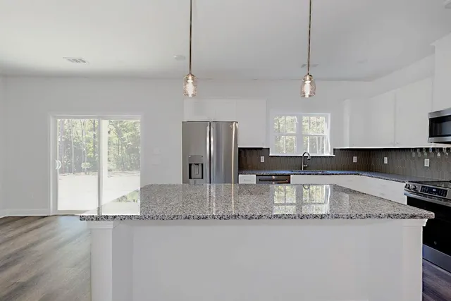 a kitchen with stainless steel appliances granite countertop a sink a stove and refrigerator