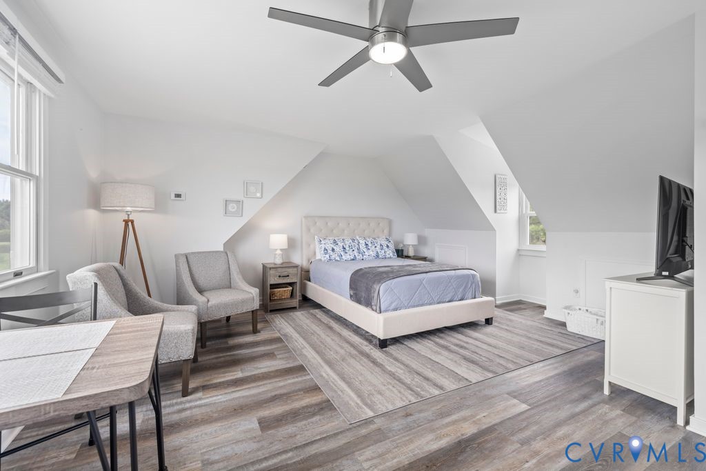 2082 Ocran Road White Stone, VA 22578 - Photo 29 of 50 a spacious bedroom with a bed a couch and a flat tv screen on a table