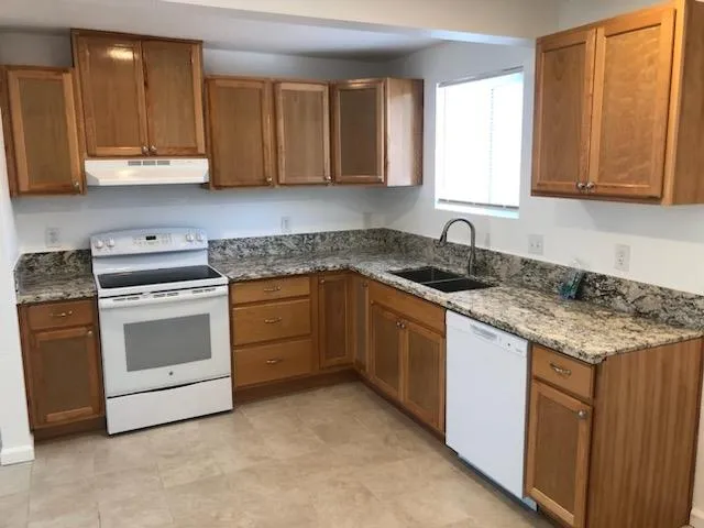 a kitchen with granite countertop white cabinets sink and stainless steel appliances