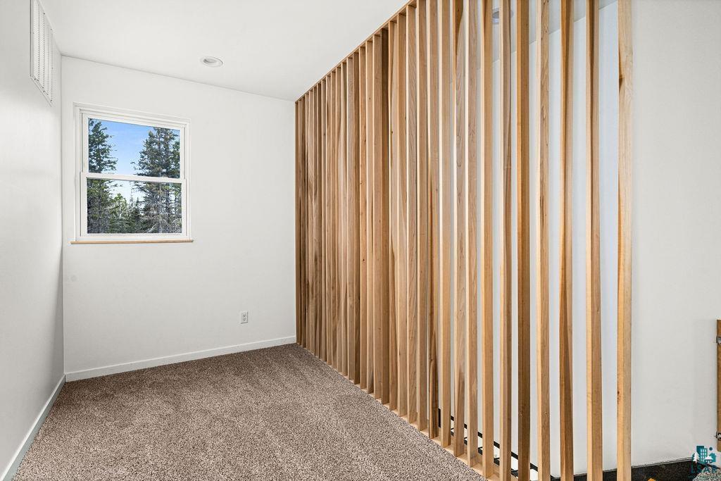 1825 East Shilhon Road Duluth, MN 55804 - Photo 32 of 37 Informal den/office w/interior room featuring a wood slat accent wall, neutral wall paint, and carpet flooring.