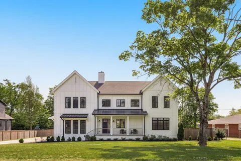 a view of a white house with a big yard and large trees