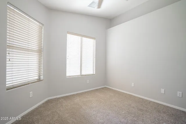 an empty room with a chandelier fan and windows