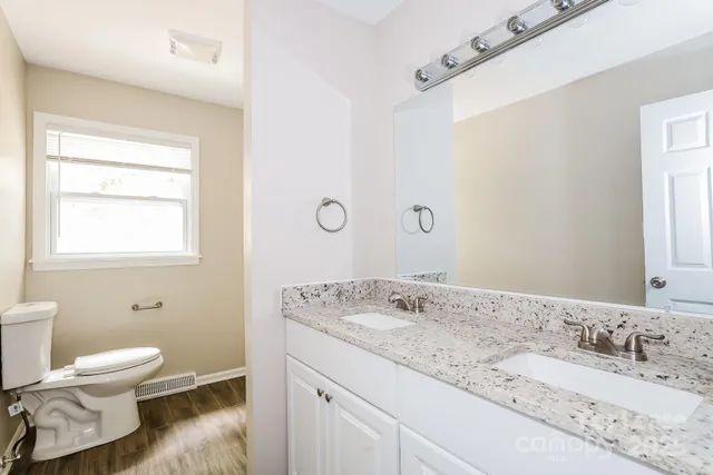 a bathroom with a granite countertop sink a toilet and a mirror