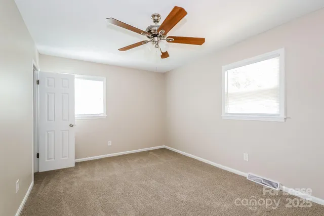 an empty room with a window and a ceiling fan